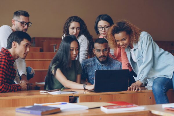 Diverse group of students gathered around laptop