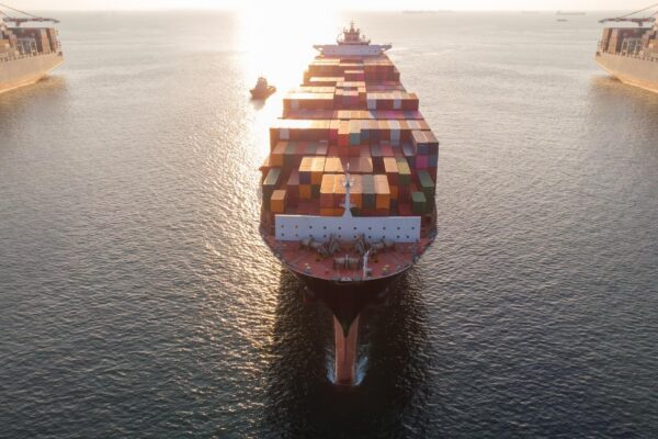 Aerial in front of cargo ship carrying container and running xAnear international custom sea port for export cargo