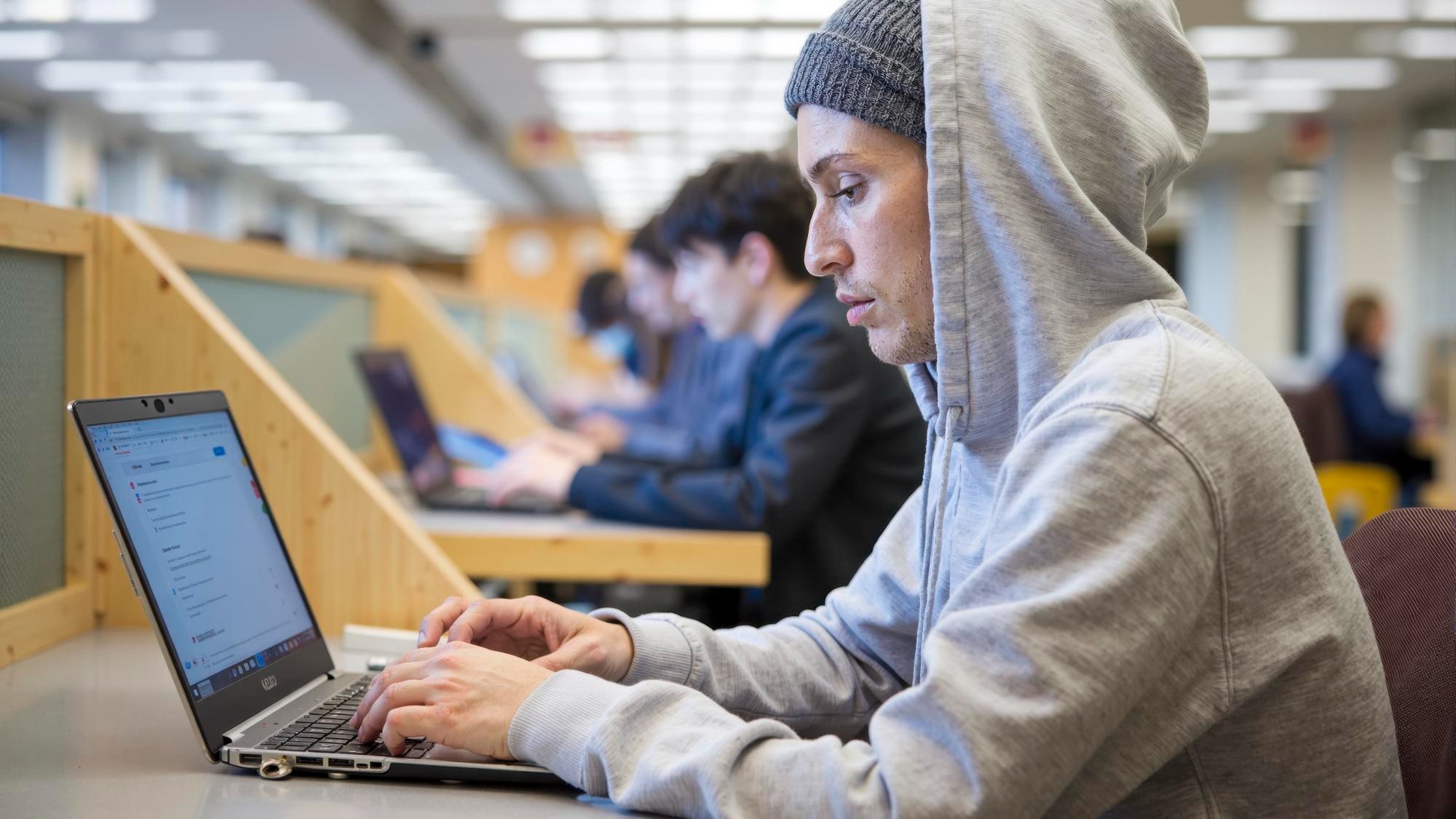 Focused student working on laptop in university library