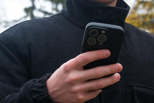 Man holding smartphone and credit card making online payment outdoors