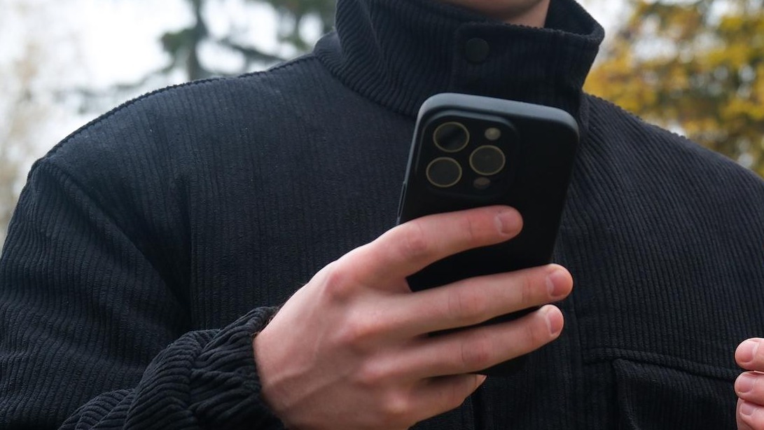Man holding smartphone and credit card making online payment outdoors