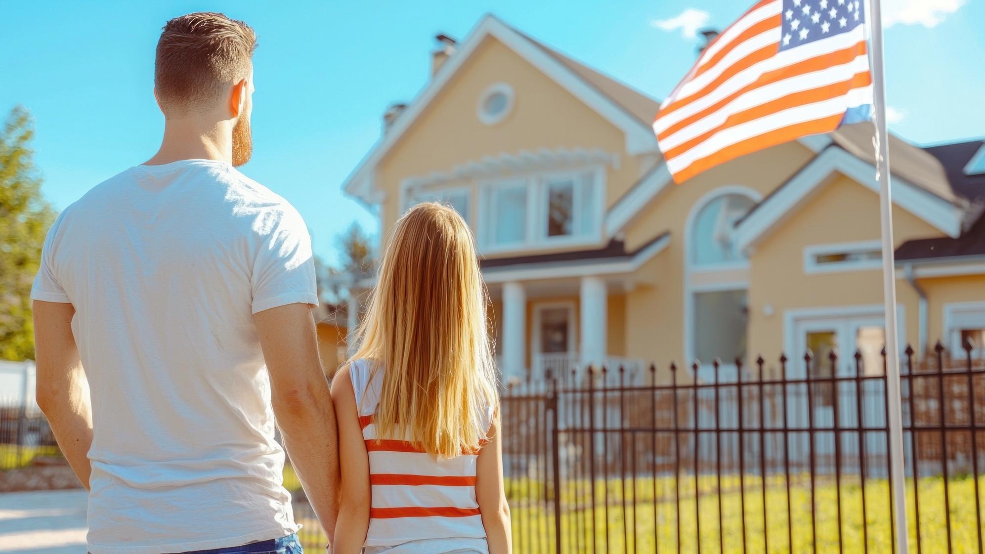 a man and a woman are standing in front of a house with a flag that says quot family quot