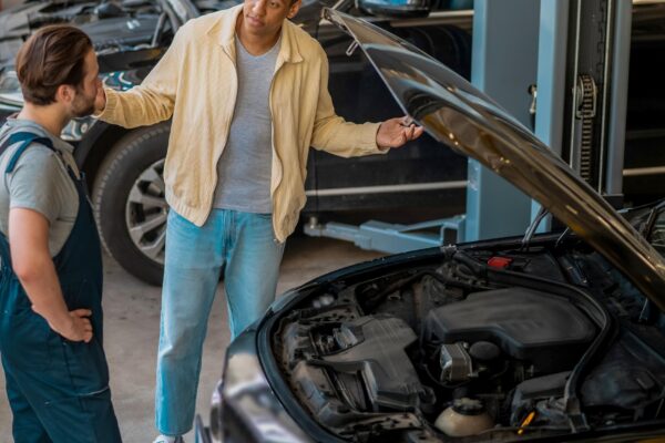 Technician in car service talking to the client