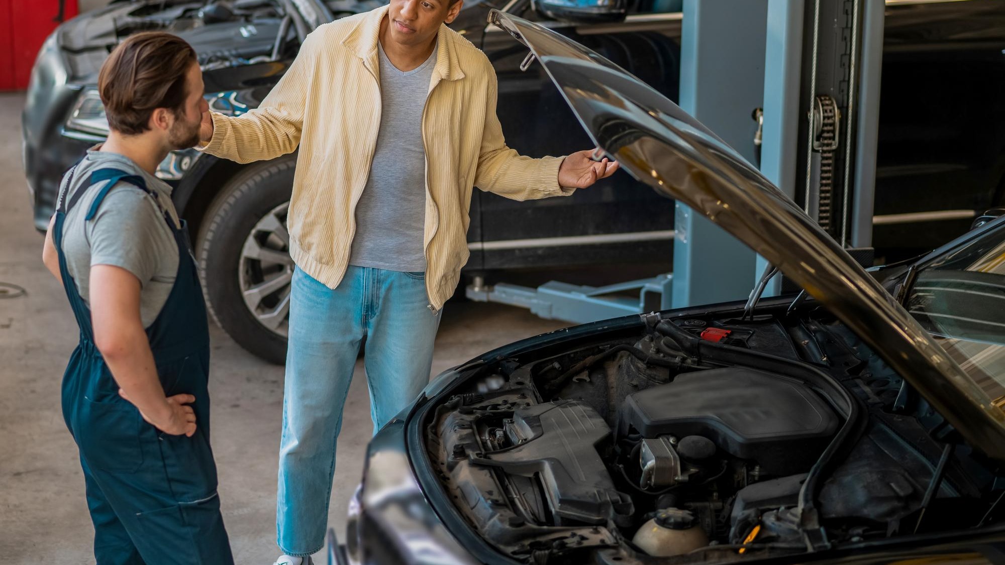 Technician in car service talking to the client