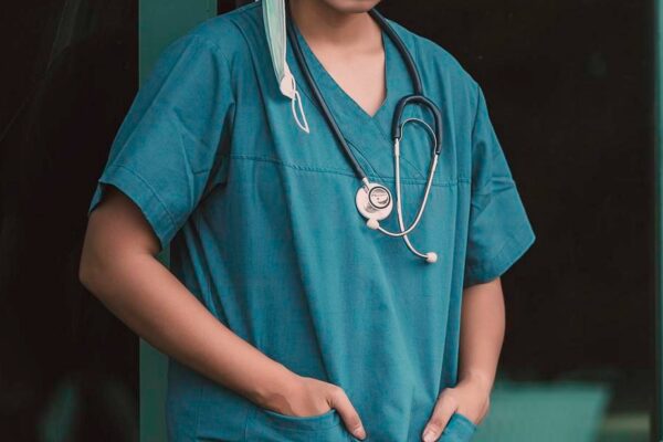 Tired depressed female asian scrub nurse wears face mask blue uniform sits on hospital floorYoung woman doctor stressed from hard work