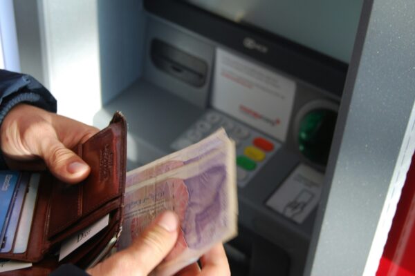 person holding brown leather wallet and banknotes