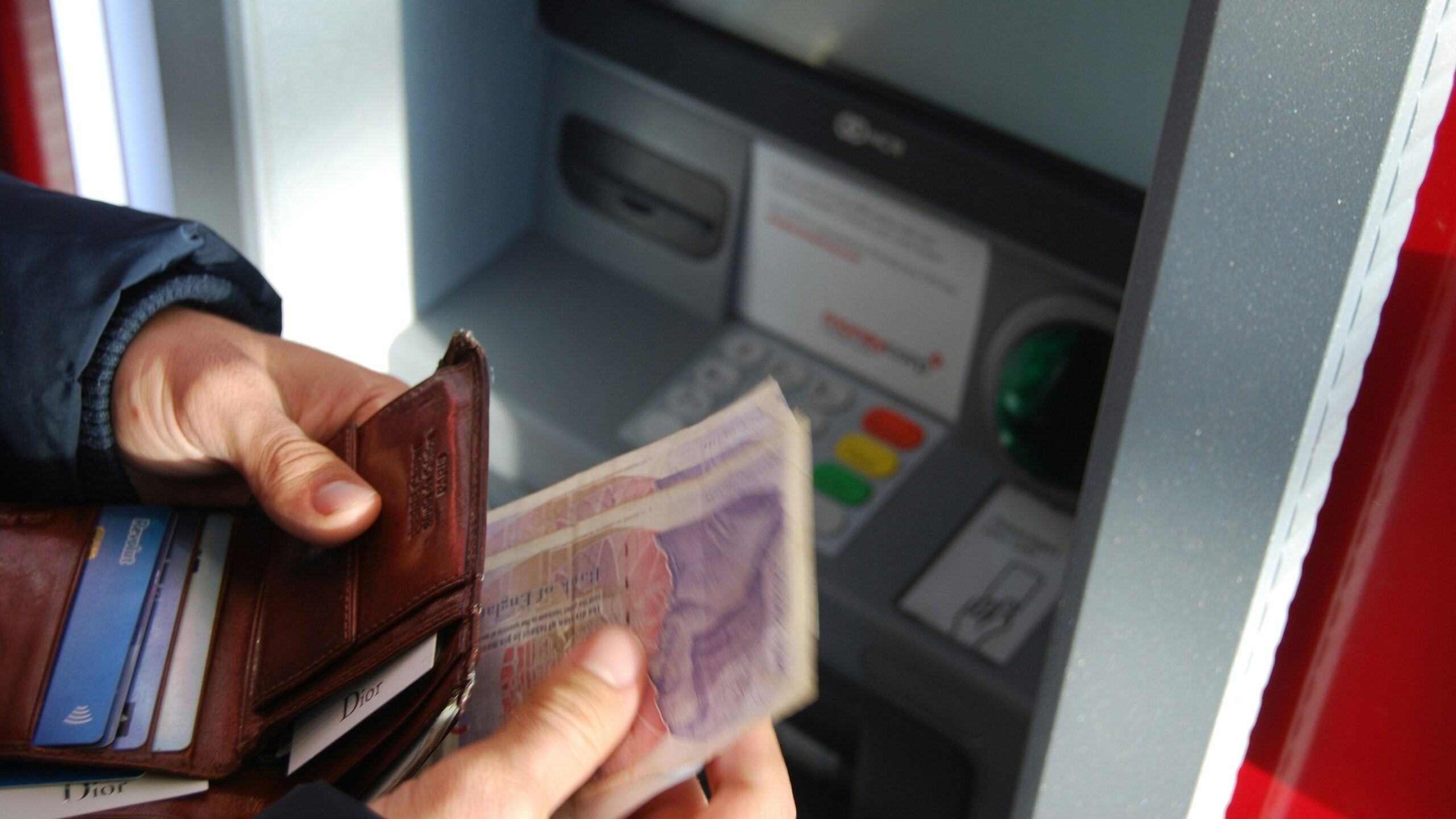 person holding brown leather wallet and banknotes