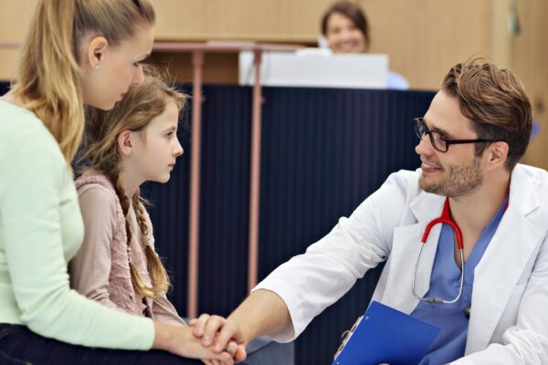 doctor welcoming mother and daughter in clinic