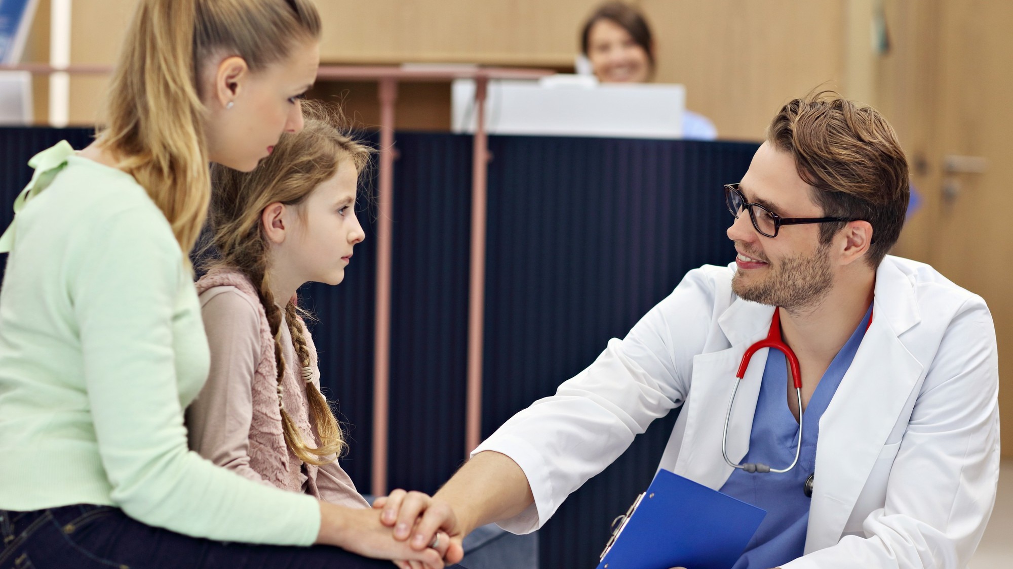 doctor welcoming mother and daughter in clinic