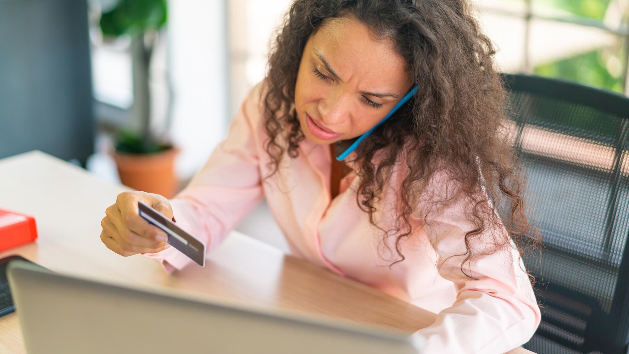 Latin woman working with hand holding card on working space at home