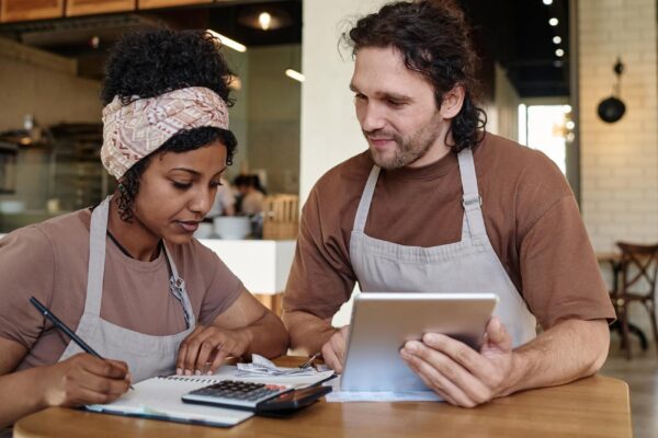 Two biracial eatery workers sitting over income calculation sitting at table after workday