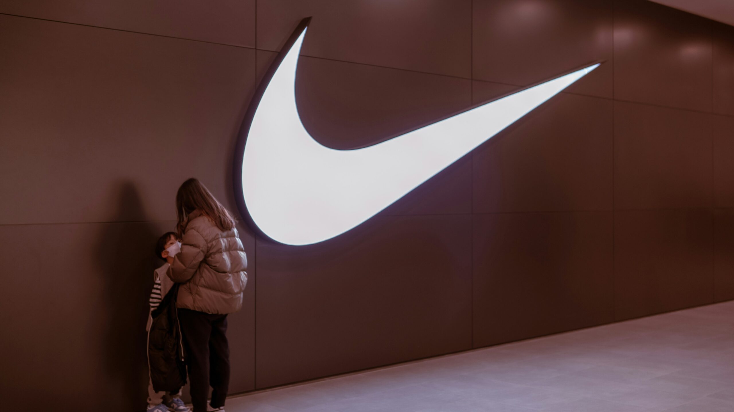 a woman standing in front of a nike logo