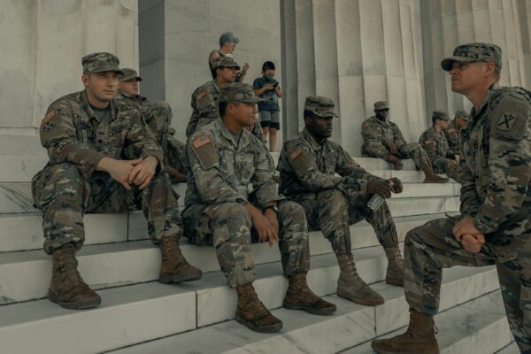 men in camouflage uniform standing near white wall
