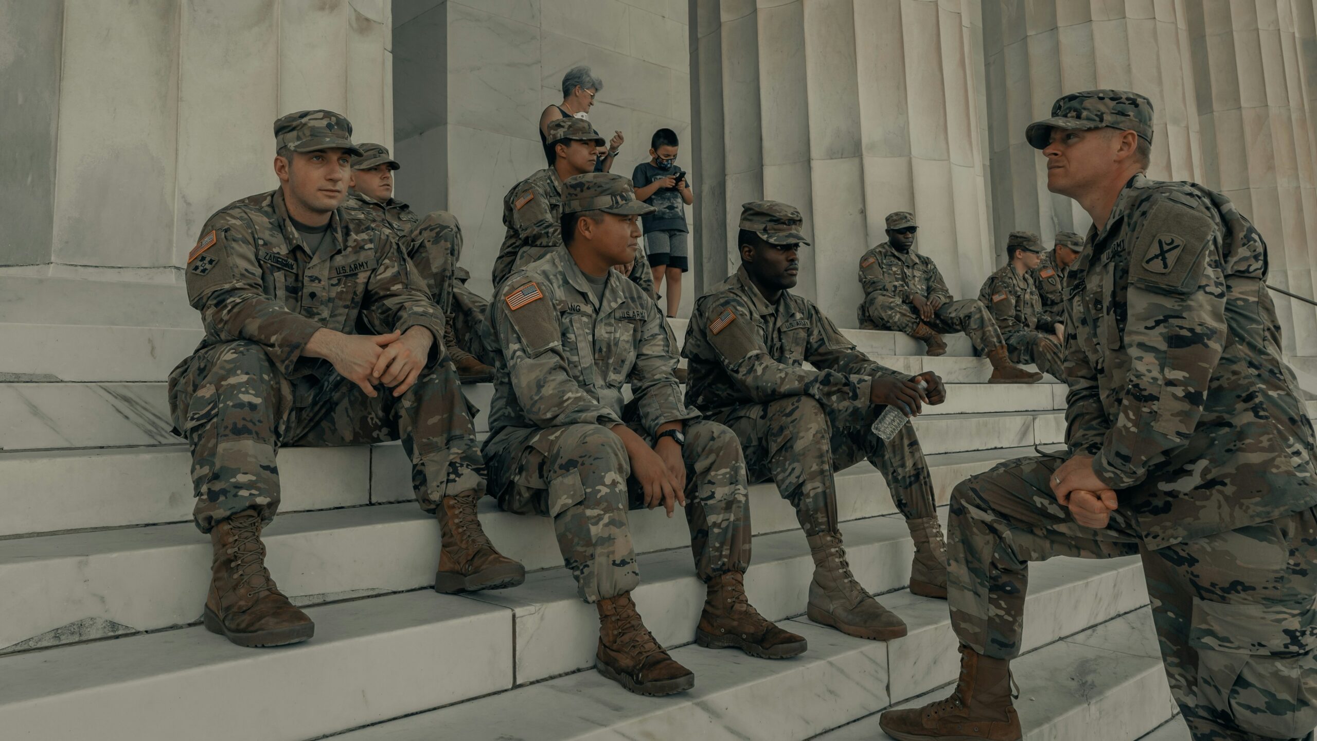 men in camouflage uniform standing near white wall
