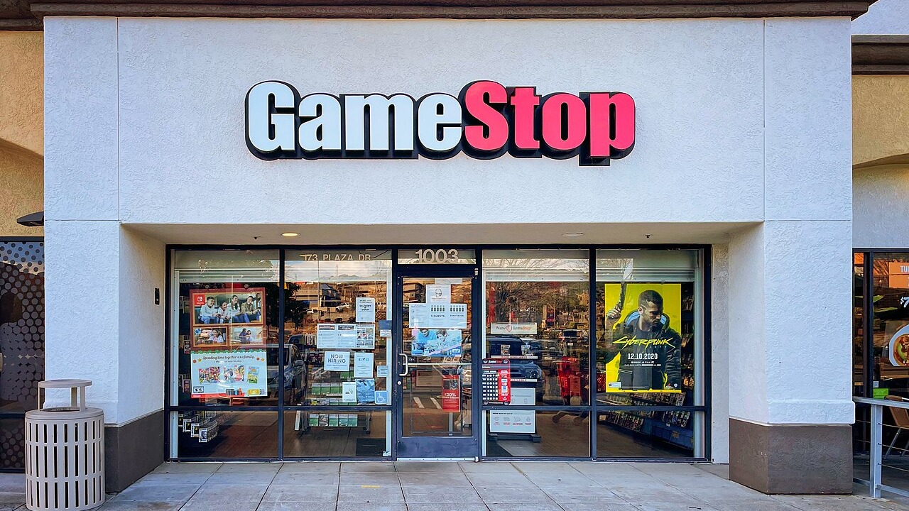 A GameStop retail store location in Vallejo, California. GameStop sells PC and console games, accessories, and merchandise. In 2021, GameStop's stock (GME on the New York Stock Exchange) was the subject of a massive "short squeeze", where retail investors from Reddit's "WallStreetBets" subreddit caused interest in the stock to surge, putting pressure on large Wall Street hedge funds who were betting on the stock to go down, and creating controversy around the Robinhood retail brokerage app.
