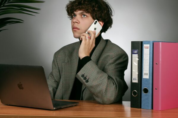a man sitting at a desk talking on a cell phone