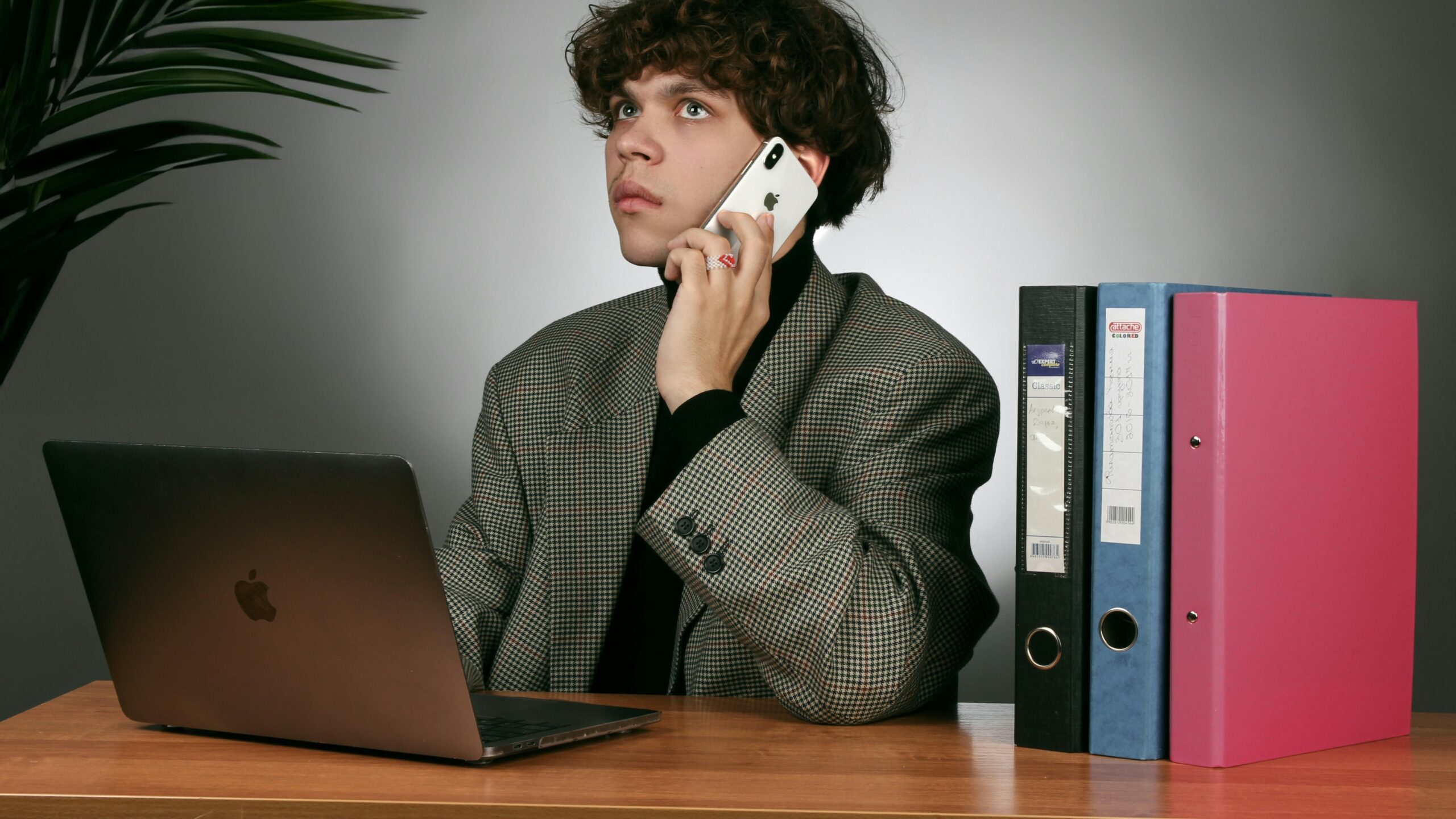 a man sitting at a desk talking on a cell phone