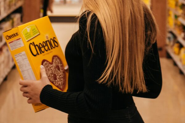 woman wearing black long-sleeved shirt holding Cheerios cereal box standing