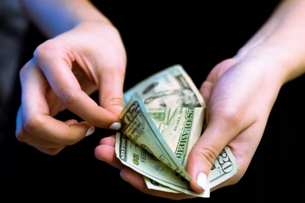 person holding fan of 100 us dollar bill