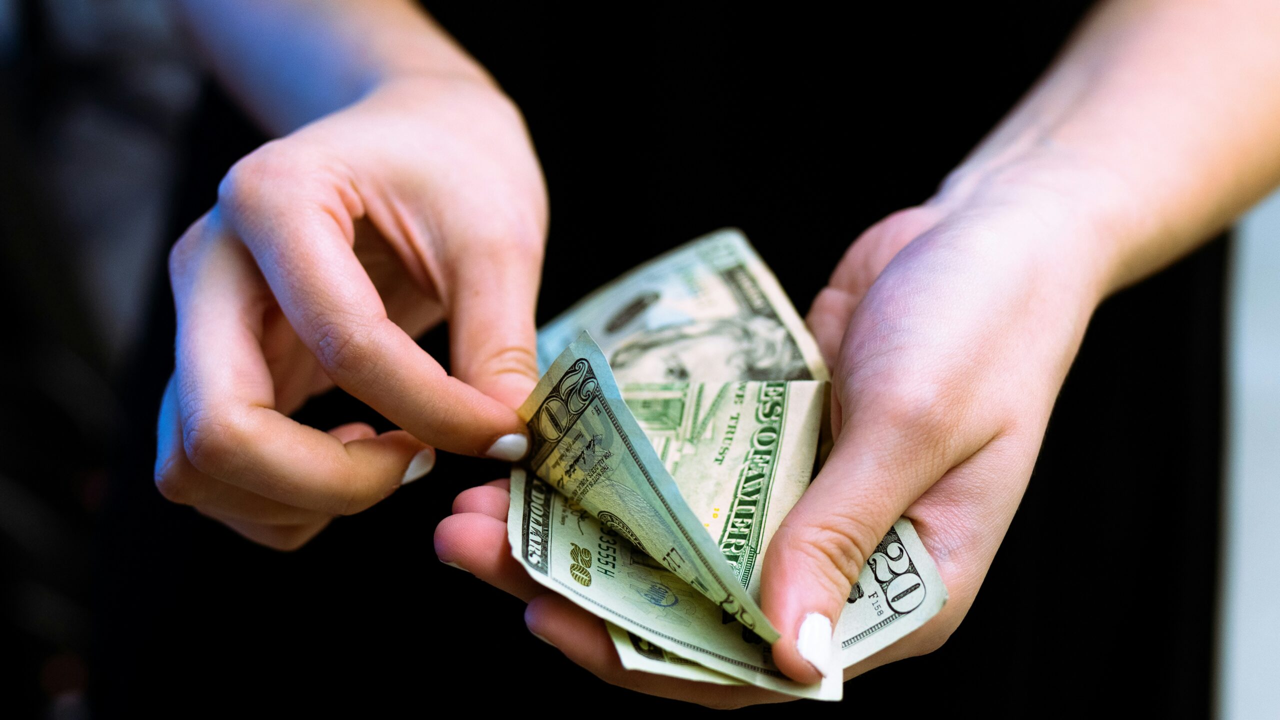 person holding fan of 100 us dollar bill