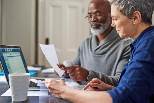 Laptop documents and finance with a senior couple busy on a budget review in the home together Accounting taxes or investment planning with a mature man and woman looking at insurance or savings