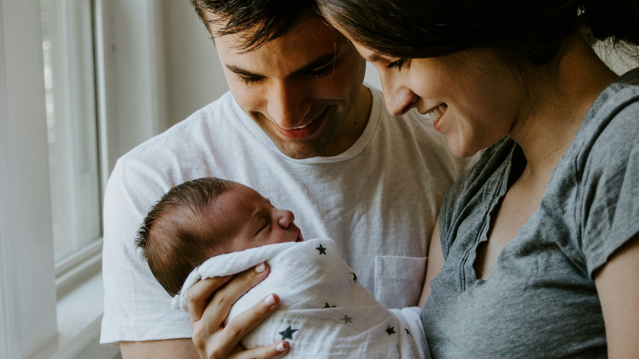 woman holding baby beside man smiling