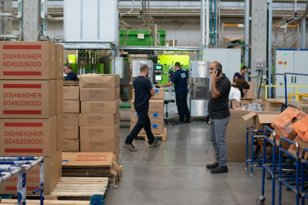 man in gray shirt standing beside brown cardboard boxes