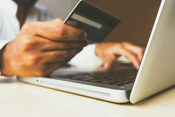person using laptop computer holding card