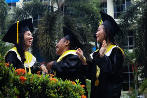 people wearing academic dress standing near blue building during daytime
