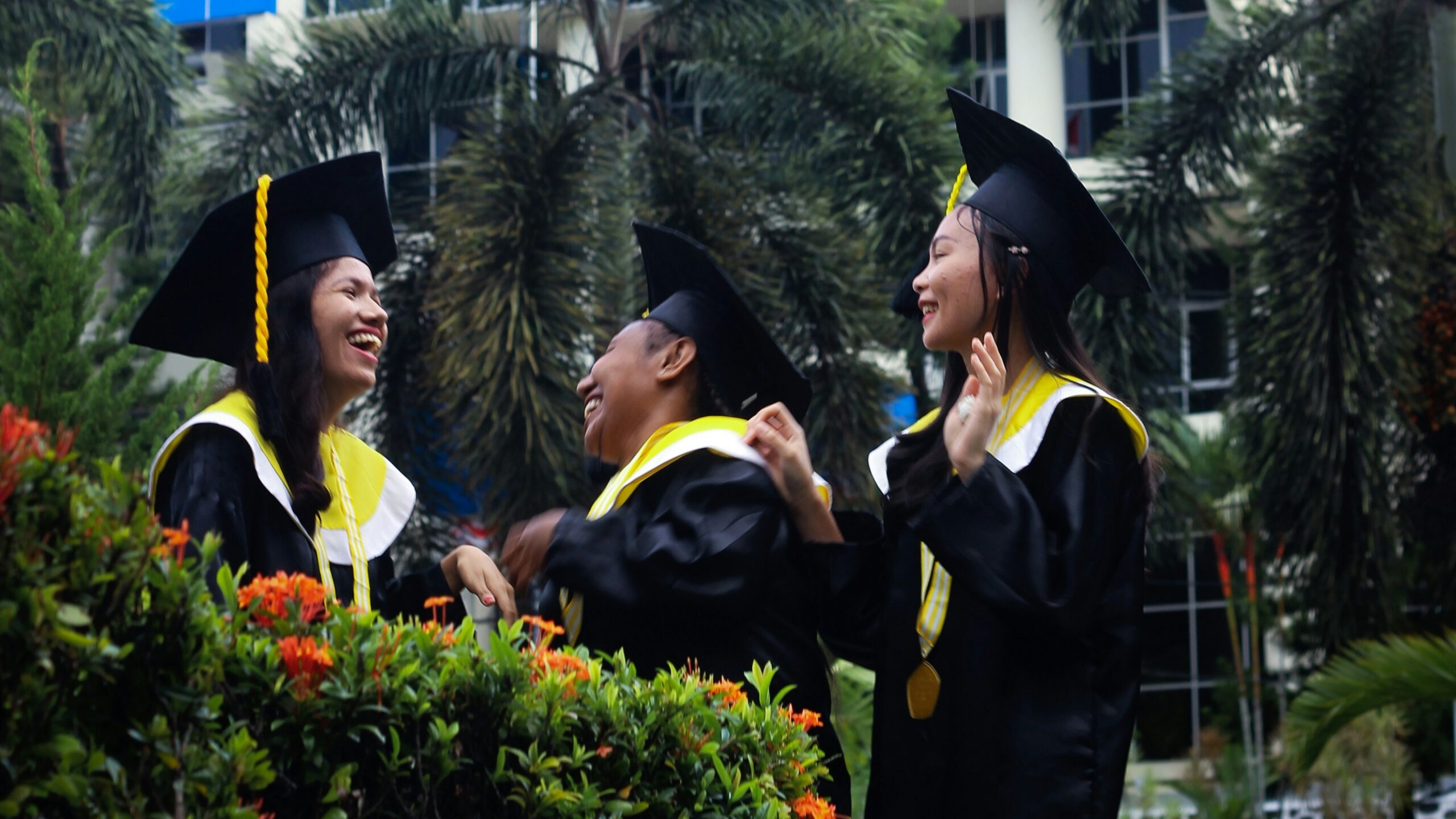 people wearing academic dress standing near blue building during daytime
