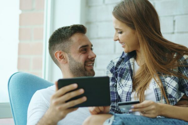 Couple looking at tablet while holding credit card