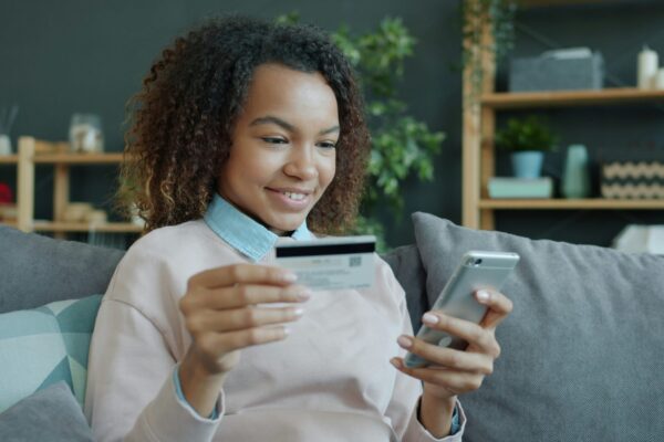 Young woman holding credit card and smartphone.