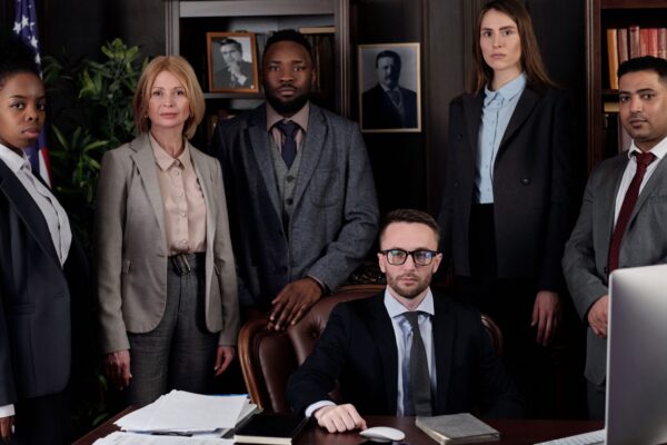 A diverse group of business professionals posing in an office, showcasing teamwork and leadership.