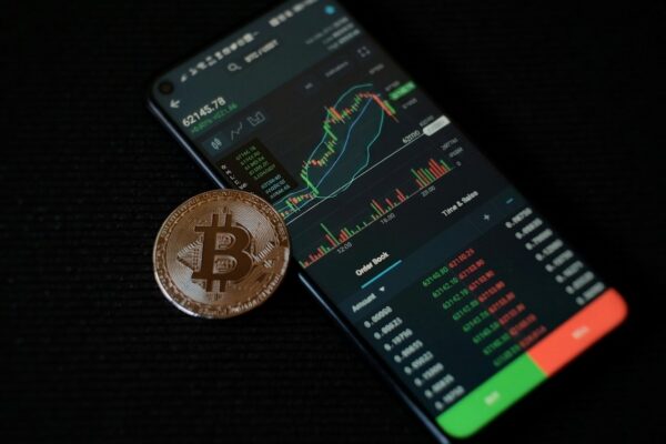 a bitcoin sitting on top of a smart phone