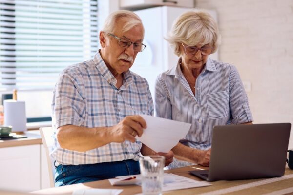 Senior couple planning their household budget while using laptop at home