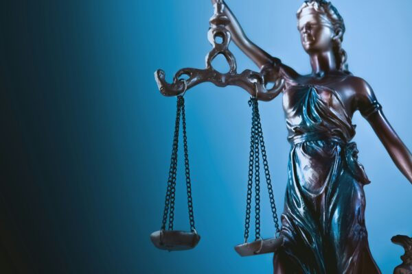 Statue of justice holding scales against blue background