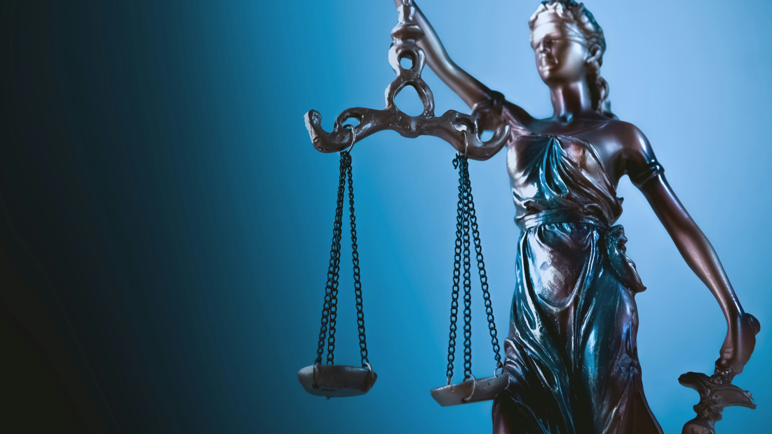 Statue of justice holding scales against blue background