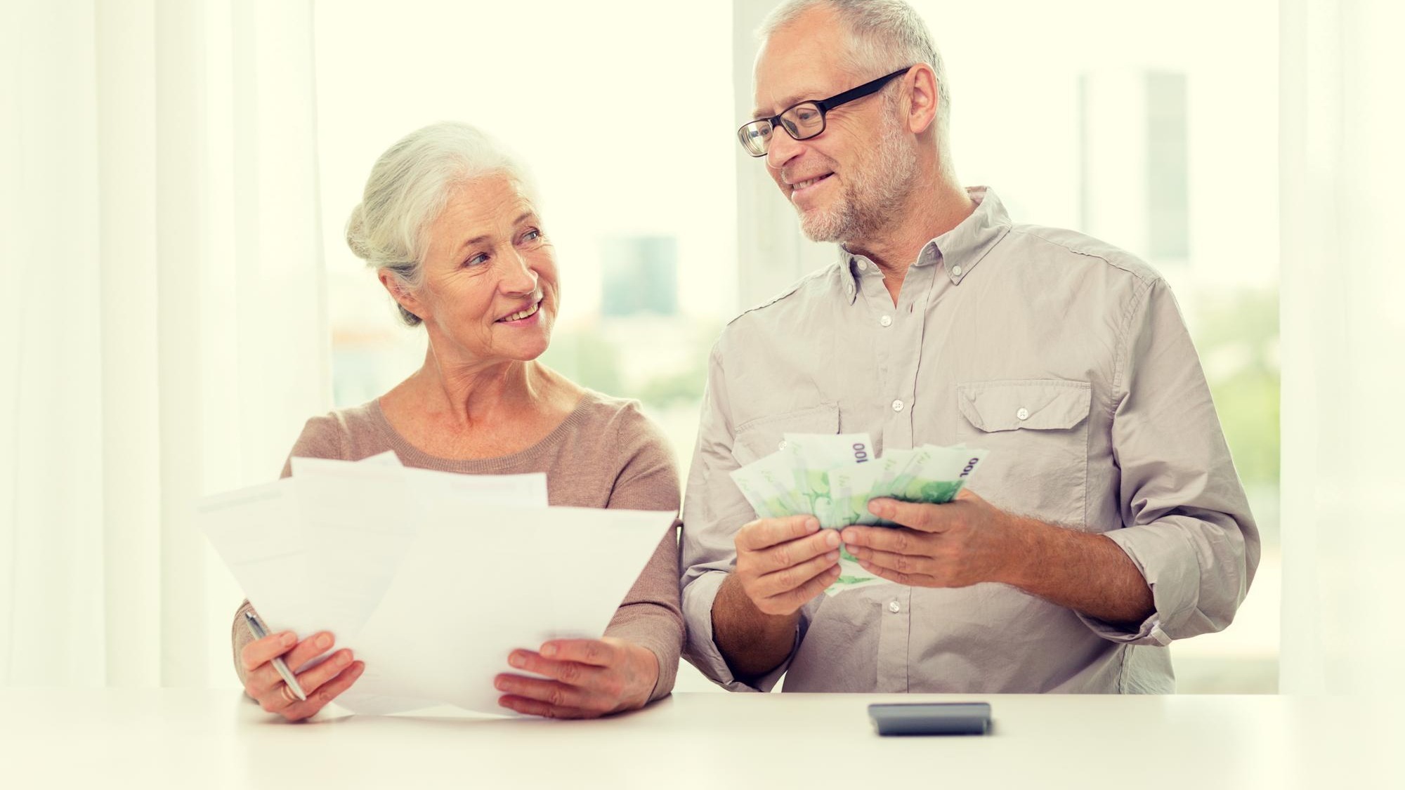 family, savings, age and people concept - smiling senior couple with papers, money and calculator at home