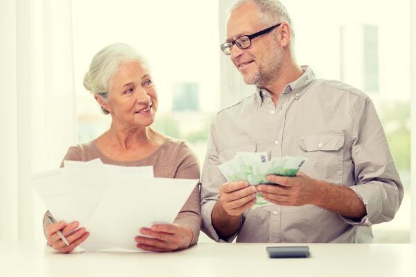 family, savings, age and people concept - smiling senior couple with papers, money and calculator at home