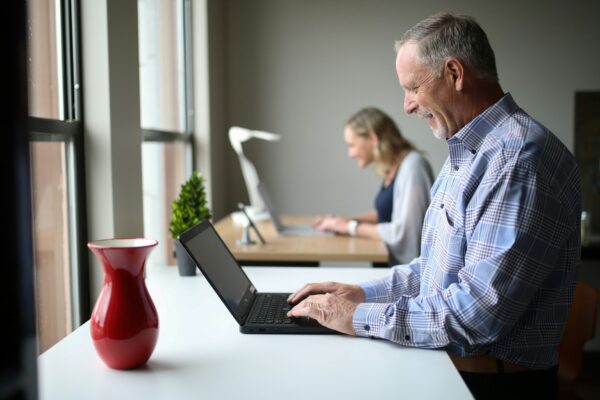 man in blue and white plaid dress shirt using black laptop computer