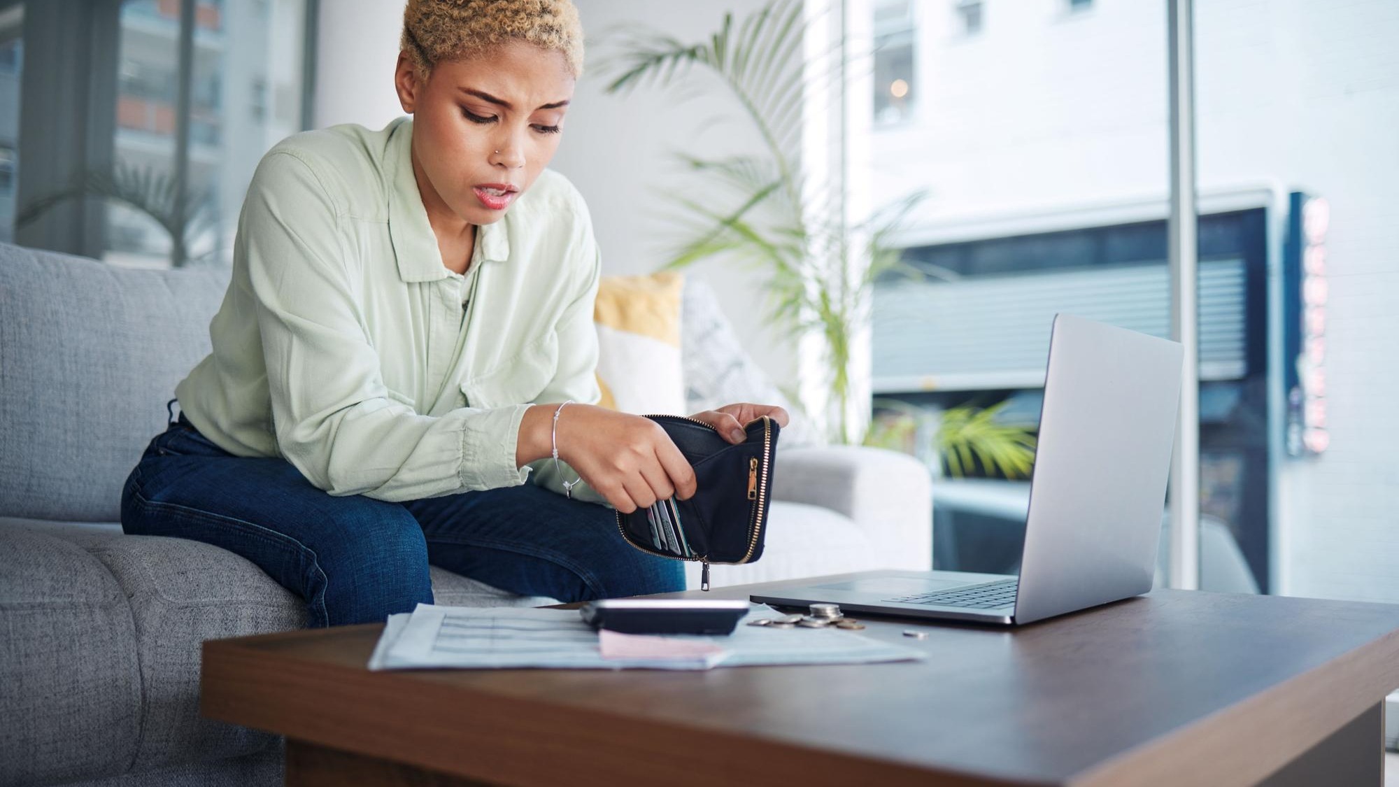 Home finance and woman with a laptop stress and calculator with budget planning review finances and inflation Person paperwork and girl on a sofa pc or counting with wallet and bankruptcy