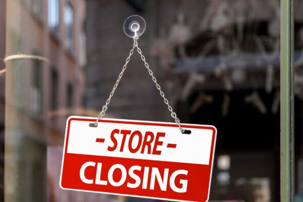 Closeup on a red sign in a window written inside in English Store closing