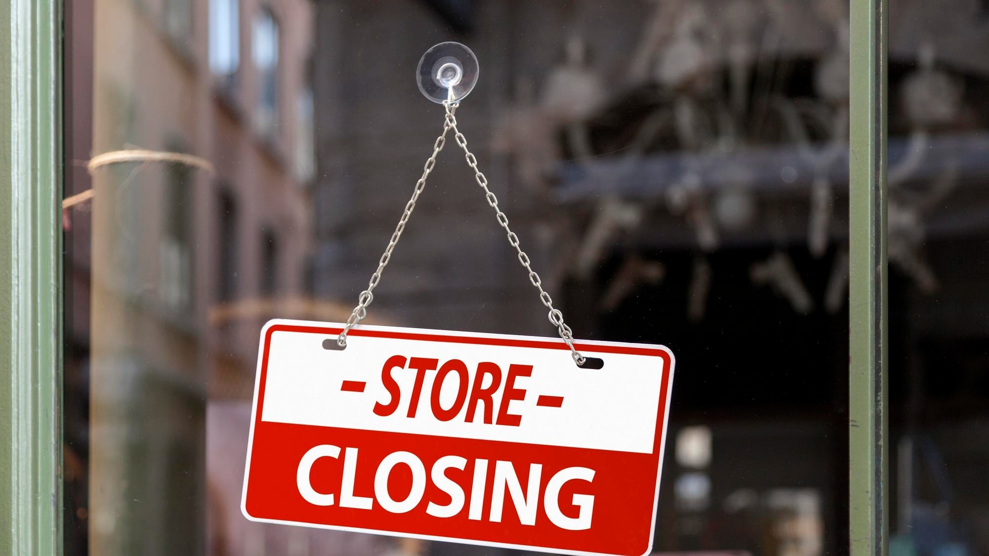 Closeup on a red sign in a window written inside in English Store closing