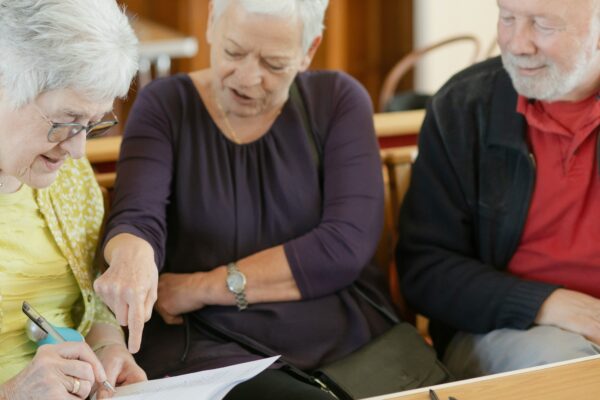 Three older adults are looking at a paper.