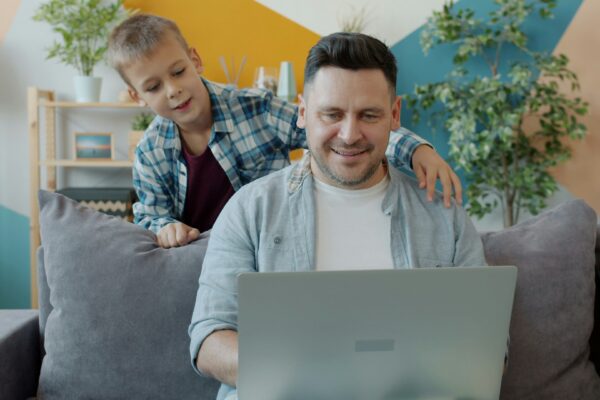 Father and son looking at laptop on couch