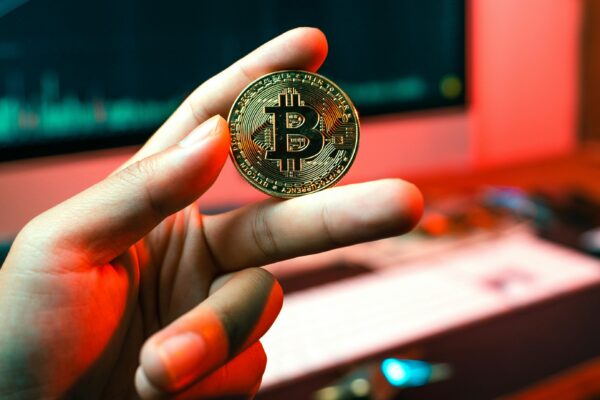 a person holding a coin in front of a computer