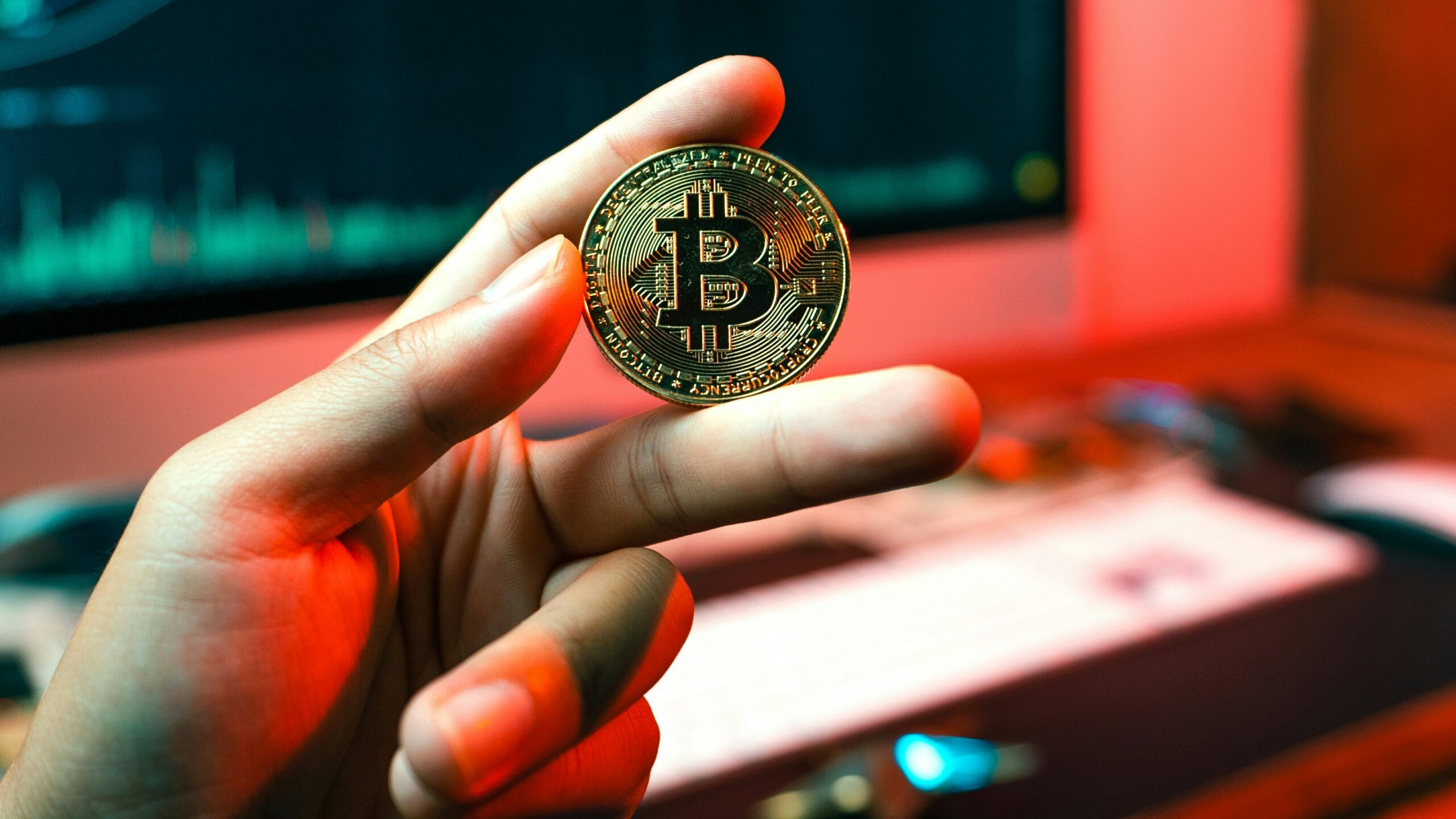 a person holding a coin in front of a computer