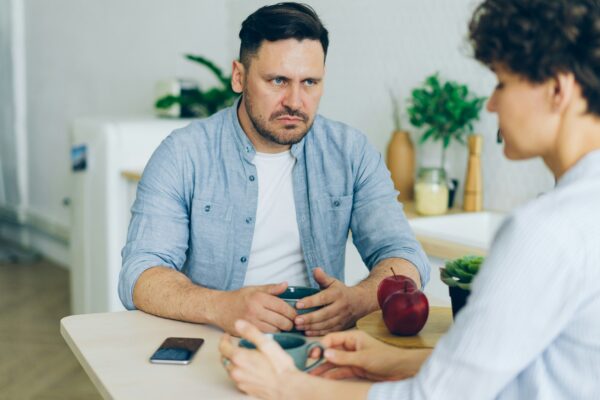 a man sitting at a table talking to a woman