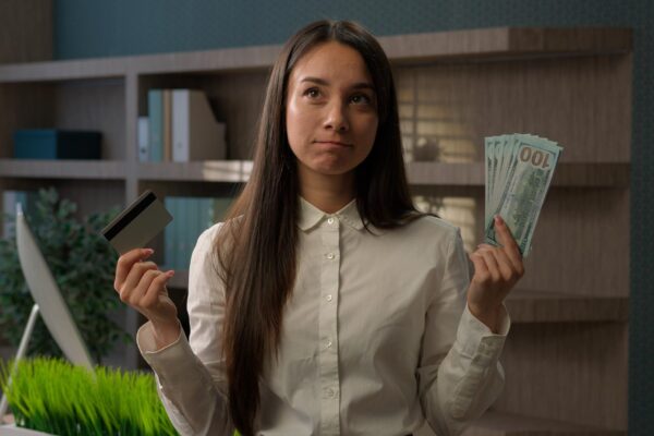 Caucasian business girl woman confused puzzled businesswoman choose between credit card and dollars