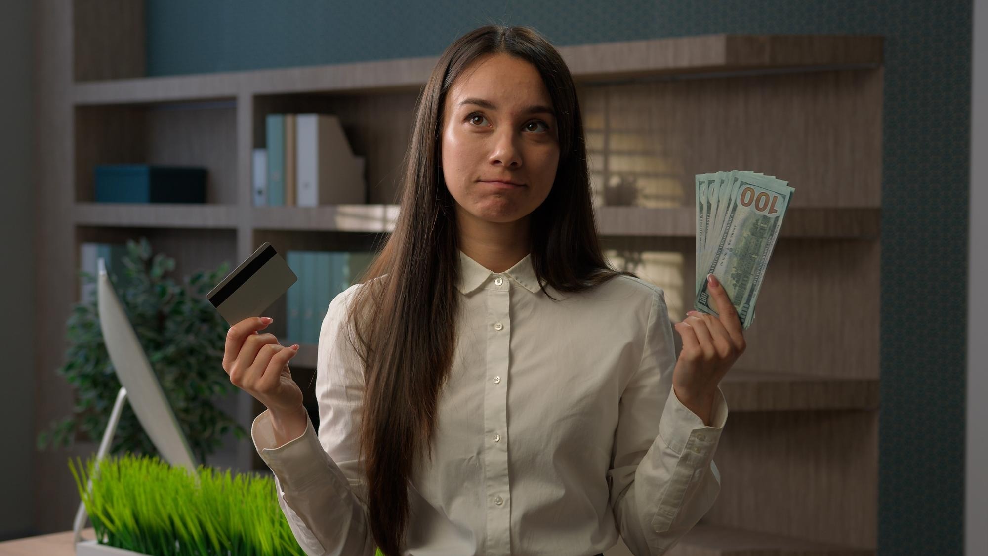 Caucasian business girl woman confused puzzled businesswoman choose between credit card and dollars